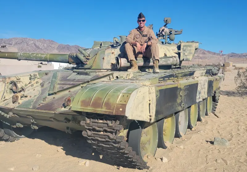 A man sitting on the back of an old tank.