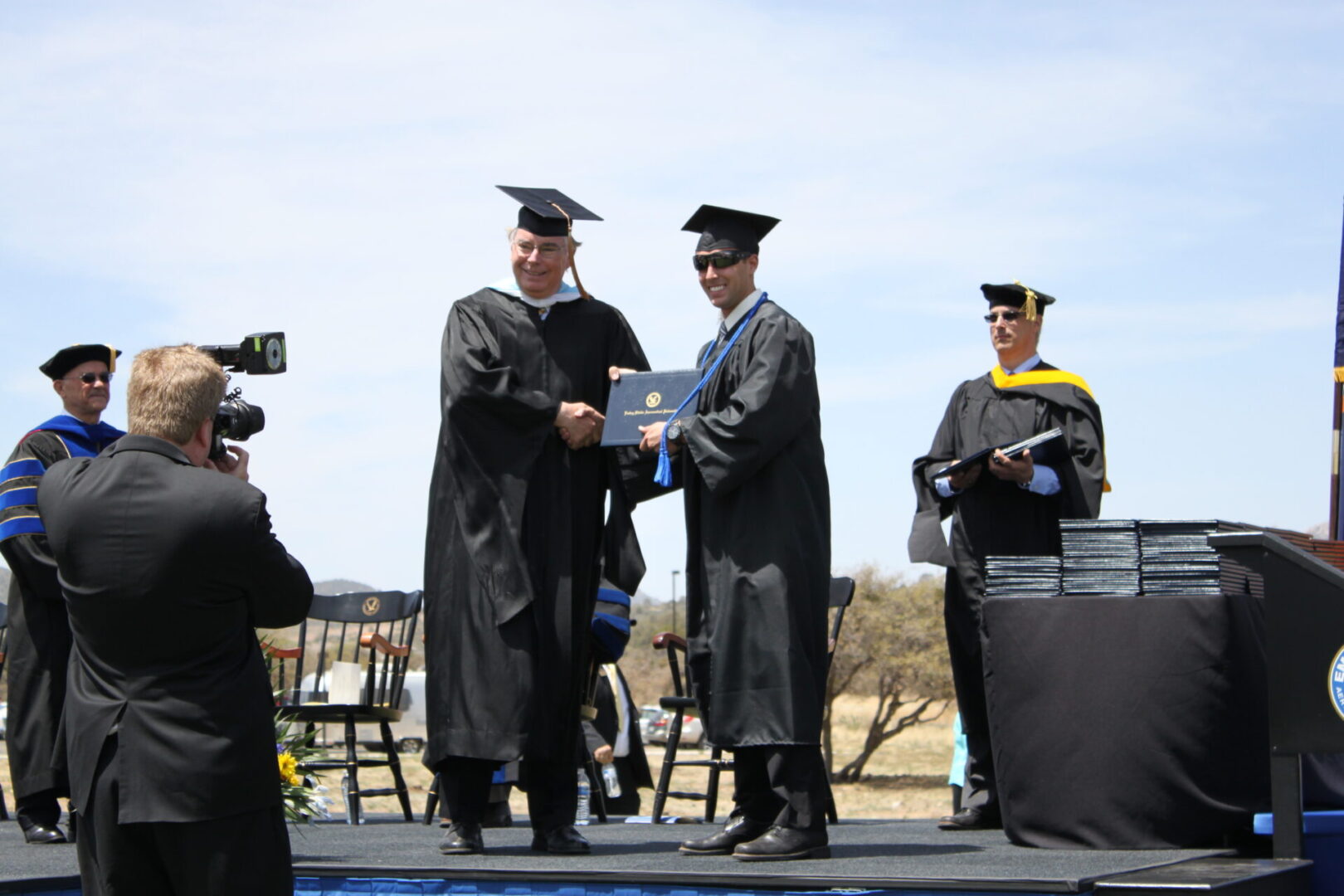 Two men in graduation robes are holding a diploma.