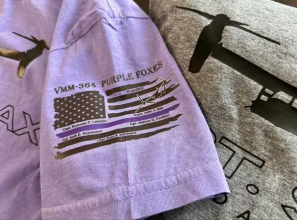 A purple flag shirt is shown on top of a blanket.