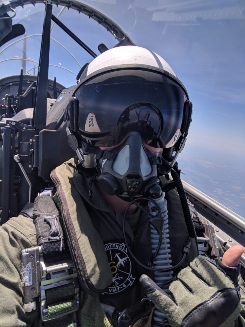 A man in military gear is sitting inside of an aircraft.